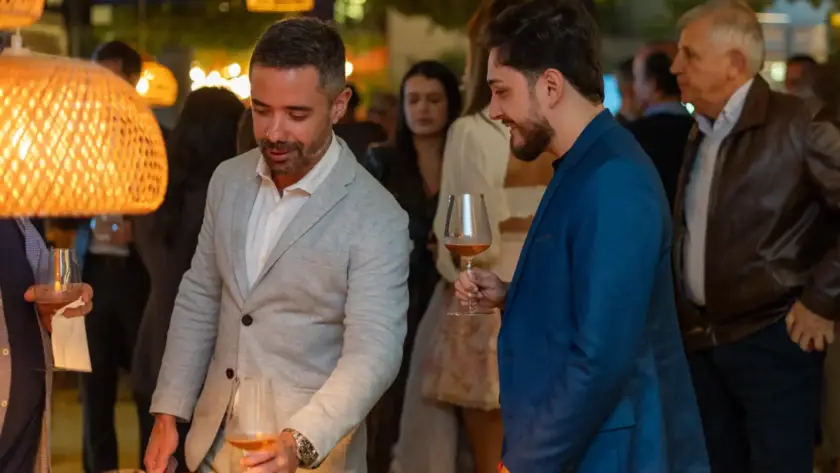 Homens apreciando vinhos em evento corporativo no restaurante Cave da cellar vinhos, com ambiente sofisticado e clima de networking