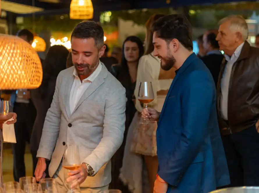 Homens apreciando vinhos em evento corporativo no restaurante Cave da cellar vinhos, com ambiente sofisticado e clima de networking