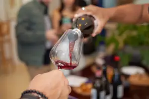 Degustação de vinho no winebar cellarcave, com foco na taça sendo preenchida e clima aconchegante ao fundo.