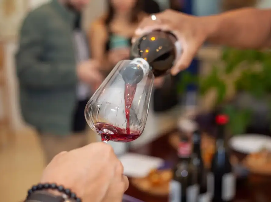 Degustação de vinho no winebar cellarcave, com foco na taça sendo preenchida e clima aconchegante ao fundo.